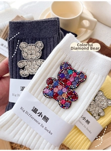 Detail of charcoal, white and yellow cotton socks with rhinestone bear pattern decoration