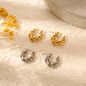 Elegant twisted rope hoop earrings in gold and silver finish on beige textured background