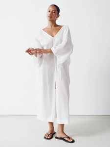 Detail of white cotton maxi dress featuring V-neckline, tie cuffs and front slit design