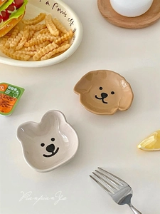 Close-up of cute bear and dog shaped ceramic dipping sauce dishes on a warm dining table