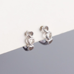 Macro view of sterling silver hoop earrings with triple hollow heart-shaped design detail