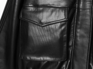 Gros plan d'une veste en cuir noir montrant les coutures de la poche et le grain du cuir