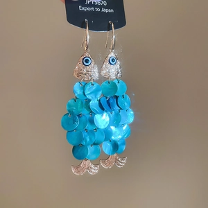 Detailed close-up of fish-shaped earrings with blue sequins and evil eye bead details