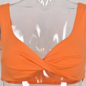 Detail of a bright orange twist-knot cropped camisole top on a clear female mannequin