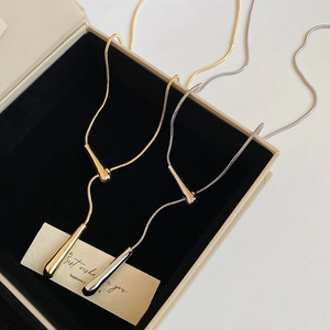 Polished gold and silver teardrop pendant necklaces in a black velvet jewelry box