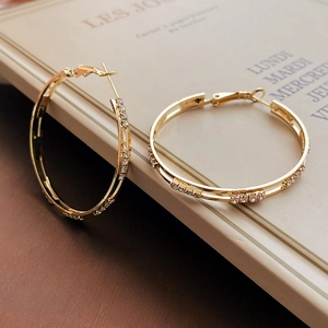 Detail of gold circular earrings with sparkling rhinestones on a French notebook