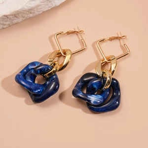 Detail of gold geometric square earrings with marble pattern dark blue resin inserts