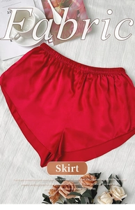 Short taille haute en satin rouge avec ceinture élastique posé sur un tissu rayé blanc