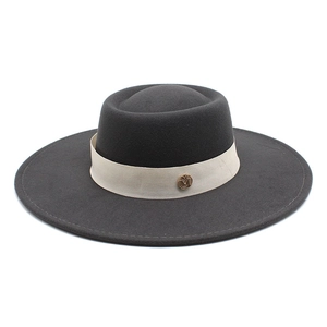 Detail view of dark grey wool felt hat with cream ribbon and gold metal logo buckle