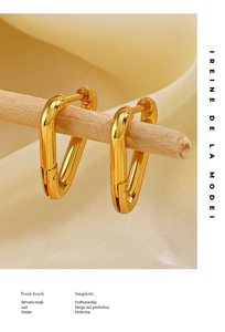 Detailed close-up of 18K gold plated triangle hoop earrings hanging on a thin wooden rod
