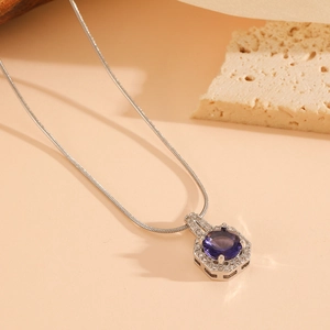 Detail of silver snake chain with a hexagonal purple gemstone pendant and zircons