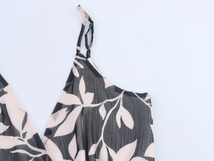 Detail of thin shoulder straps and cream leaf print on black chiffon dress fabric