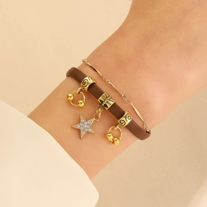 Detail of layered brown leather and gold chain bracelet with sparkling star pendant