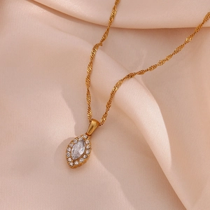 Macro detail of gold marquise pendant necklace with white zircon on pink silk fabric