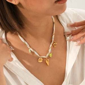 Détail du collier tissé en ruban de soie avec pendentifs coquillage et cœur sur mannequin
