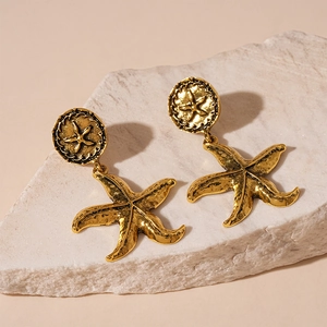 Detail shot of vintage golden starfish earrings with textured metallic finish on stone