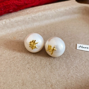 Vue macro détaillée de boucles d'oreilles perles blanches avec caractères dorés