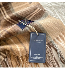 Detailed macro view of the 100% blend wool fabric texture and fringe on the plaid scarf