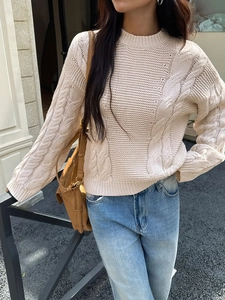 Close-up of beige cable knit texture and crew neck detail on women's winter sweater