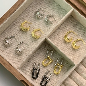 Detailed view of irregular tin foil texture earrings in gold and silver within a wooden box