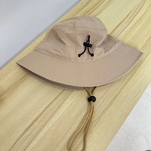 Detail of beige sun hat featuring a wide brim and adjustable black drawstring buckle
