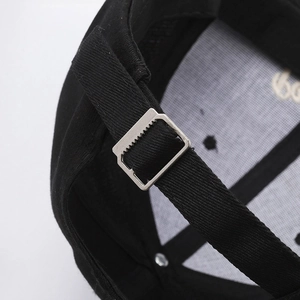 Adjustable back strap of a black embroidered baseball cap with a silver metal buckle