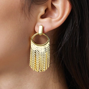 Detail of golden tassel earrings with industrial lines and metal weave on model