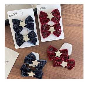 Close-up of velvet bow hair clips with silver star glitter in navy and burgundy
