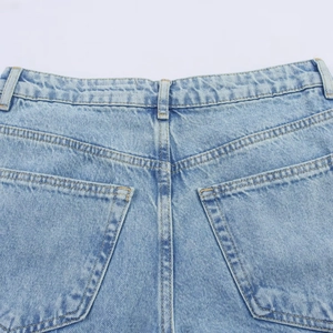 Detail of high waist light blue denim jeans showing back pockets and stitching texture