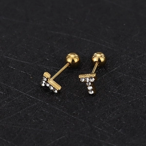 Macro detail of gold-plated T-letter stud earrings with sparkling white cubic zirconia