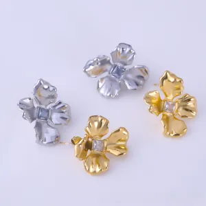 Macro view of gold and silver flower stud earrings with center square gemstones