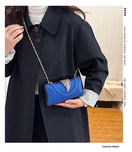 Close-up of blue glitter evening bag with gold leaf clasp and elegant chain strap