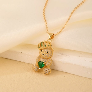 Detailed close-up of a gold-plated bear necklace with micro-pave diamonds and green heart gem