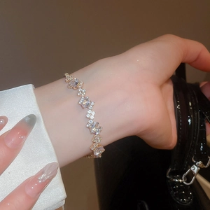 Close-up of gold clasp bracelet with shimmering zircon stones on a woman's wrist