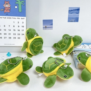Cute green sea turtle plush keychain with silver chain in a cozy lifestyle setting