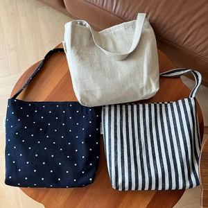Three canvas shoulder bags in solid, polka dot, and striped patterns on a wooden table