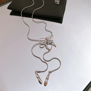 Detail of silver balletcore necklace featuring a bow and ballet slippers pendants