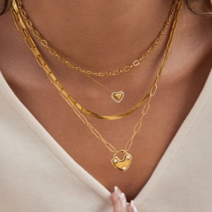 Ensemble de colliers dorés superposés avec pendentif cœur et breloque cadenas perlé
