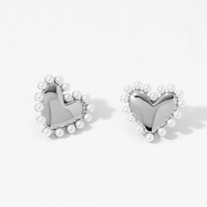 Gros plan de boucles d'oreilles cœurs en argent avec perles blanches sur fond blanc