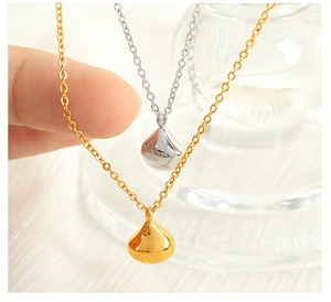 Macro shot of minimalist gold and silver teardrop pendant necklaces held by hand