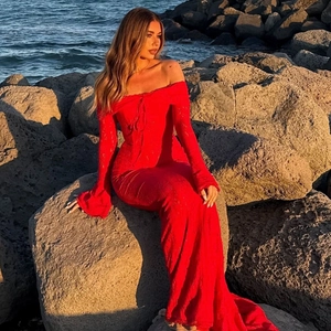 Detail of red lace off-shoulder maxi dress with flare sleeves against a coastal backdrop
