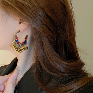 Detail of vintage gold hoop earrings with colorful gemstones and tassel beads on model