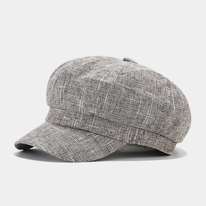 Detail view of the grey tweed newsboy cap showing textured fabric and structured brim
