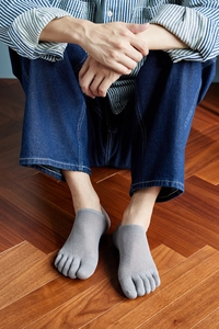 Close-up of men's grey five-finger socks with breathable mesh cotton on wooden floor