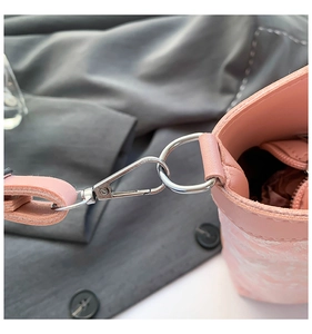 Close-up of pink leather bucket bag shoulder strap with silver metal spring hook and D-ring