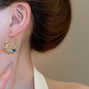 Close-up of Bohemian hoop earrings featuring colorful natural crushed stones and gold beads