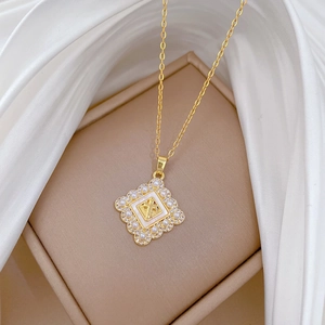 Elegant gold titanium necklace with pearl-bordered square cross pendant on white silk