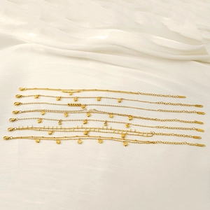 Flat lay of multiple 18K gold plated anklets with heart charms and pearls on white silk