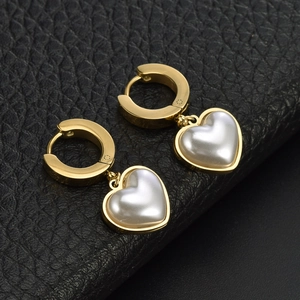Elegant gold heart earrings with pearl drops on textured black background
