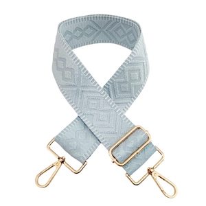 Detail of light blue 5cm wide bag strap with golden buckles and woven geometric pattern
